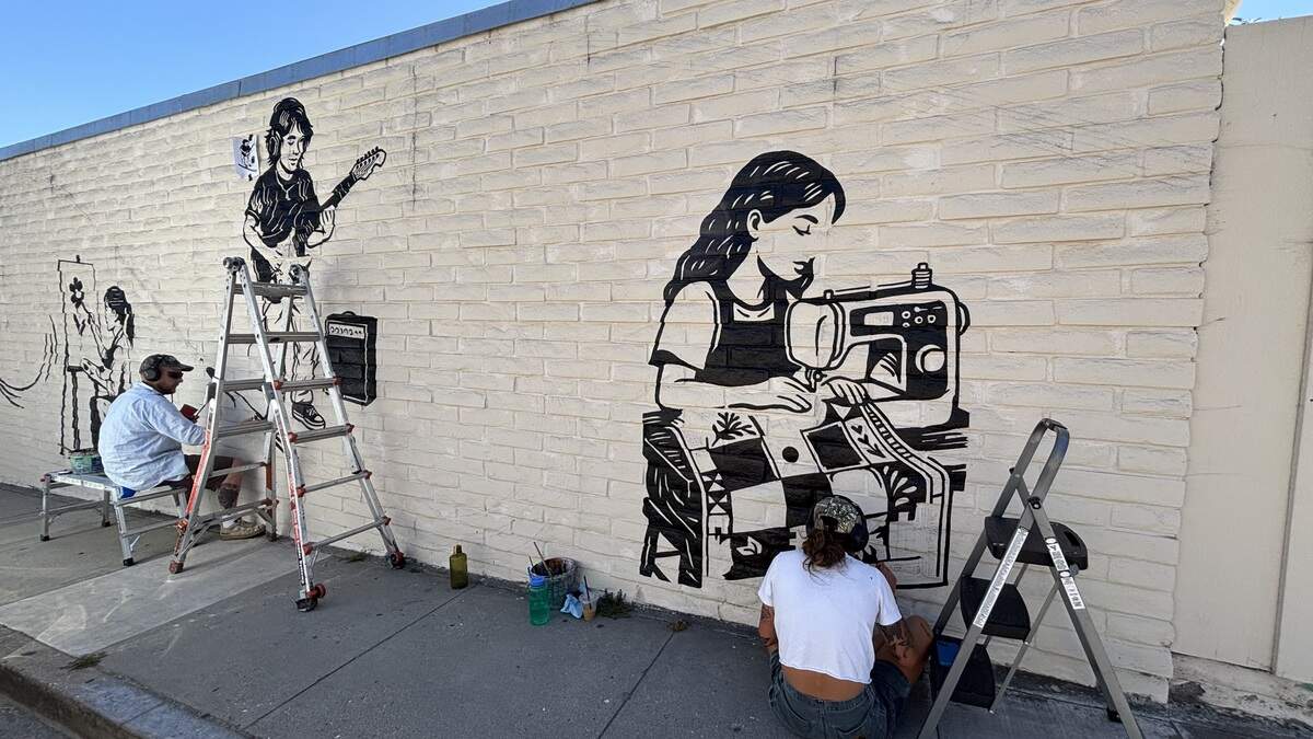 Painting business Canned Pineapple paints the mural on the side of Village Creative’s building, seen on July 28, 2026.